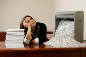 Frustrated woman attempting to shred documents in office